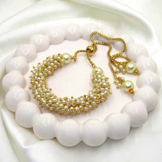 Pearl Heritage Golden Bracelet by Enava featuring handcrafted ivory pearl beadwork, polished gold-tone detailing, adjustable slider chain with pearl drop accents, elegant luxury bracelet for weddings, festive occasions, bridal wear, party styling, and premium ethnic jewellery.
