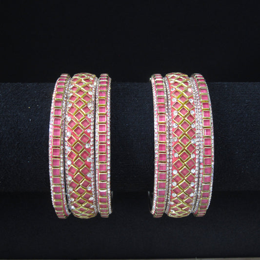 Four wide silver-toned bangles decorated with pink rectangular stones and gold diamond-pattern inlays, displayed on a black background.