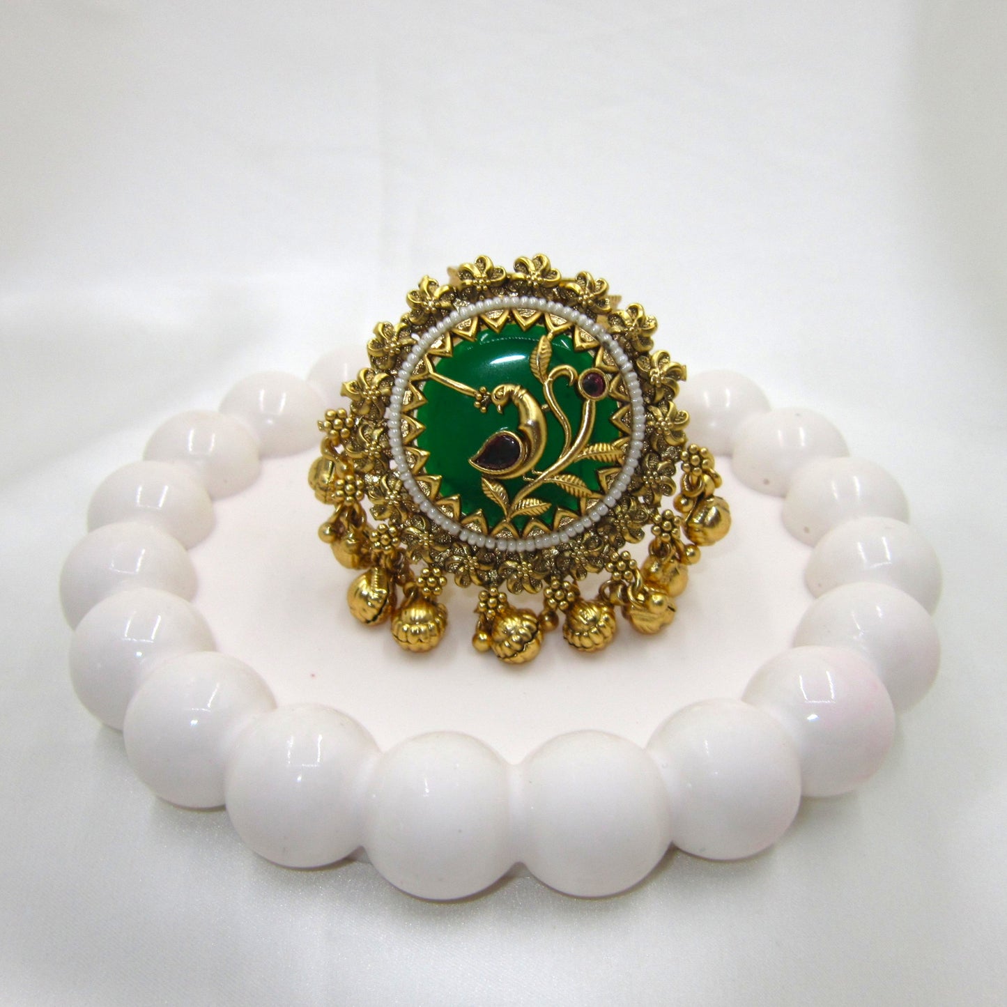 Vanmayuri Heritage Antique Emerald Green Ghungroo Ring by Enava featuring an adjustable antique gold statement ring with emerald green enamel, floral vine design, pearl border and decorative ghungroo charms, perfect for wedding jewellery, festive wear and traditional ethnic outfits.