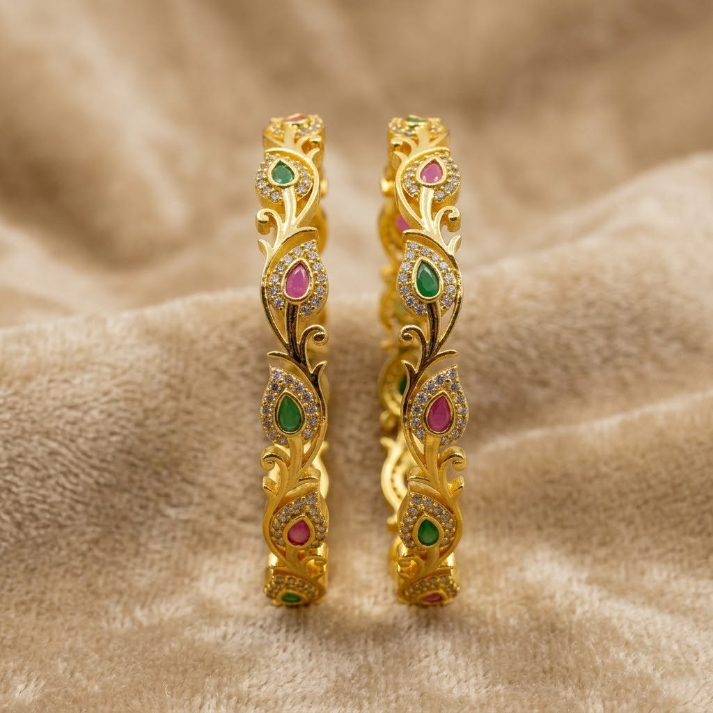 Floral Bliss Gold Plated AD Bangles by ENAVA featuring sparkling Cubic Zirconia AD stones with ruby pink and emerald green teardrop accents in an elegant floral vine design. Premium gold plated bridal bangles perfect for weddings, festive occasions, party wear, and ethnic jewellery collections.