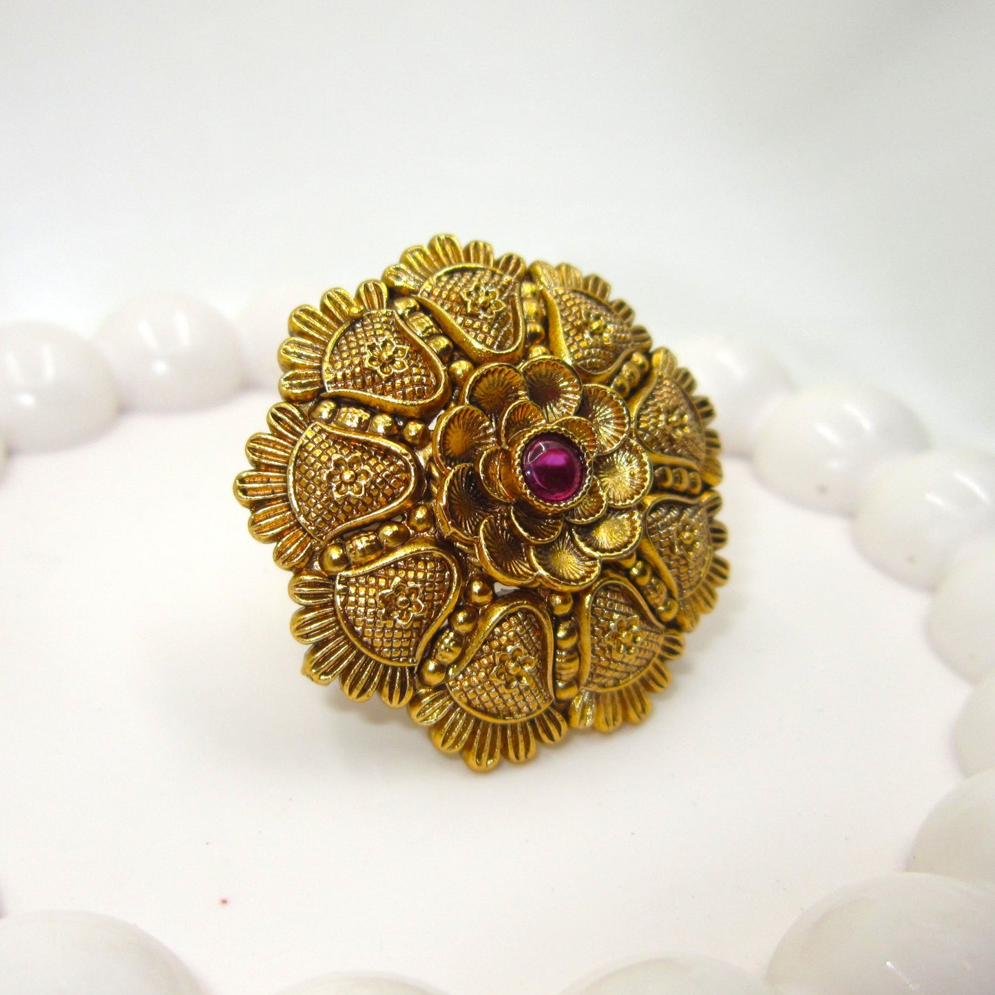 Kamalika Heritage Floral Antique Golden Finish Ring by Enava featuring an intricate floral heritage design with a ruby pink centre glass stone, antique golden finish, adjustable ethnic statement ring for weddings, festive occasions, and traditional Indian wear.