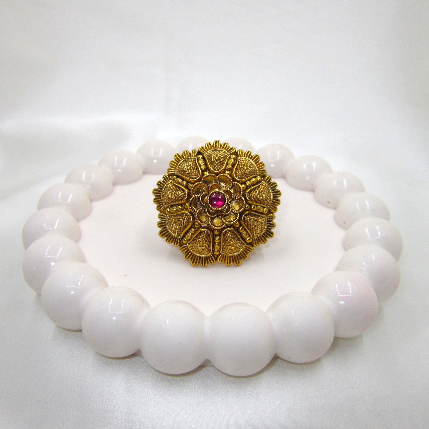Kamalika Heritage Floral Antique Golden Finish Ring by Enava featuring an intricate floral heritage design with a ruby pink centre glass stone, antique golden finish, adjustable ethnic statement ring for weddings, festive occasions, and traditional Indian wear.