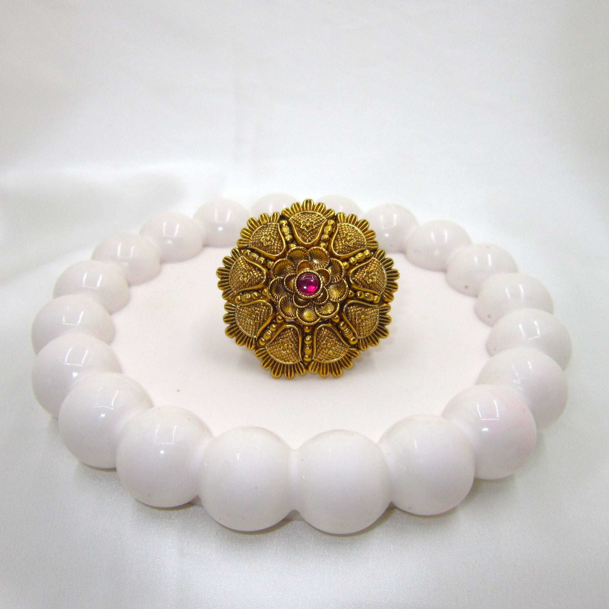 Kamalika Heritage Floral Antique Golden Finish Ring by Enava featuring an intricate floral heritage design with a ruby pink centre glass stone, antique golden finish, adjustable ethnic statement ring for weddings, festive occasions, and traditional Indian wear.