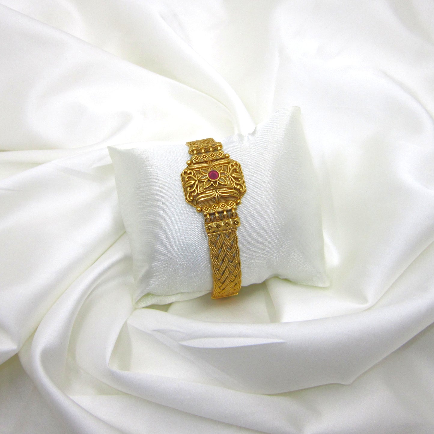 Kusum Heritage Rajwadi Bracelet by ENAVA featuring antique gold finish, floral centerpiece, ruby red stone accent, and intricate braided Rajwadi craftsmanship for weddings and festive wear.