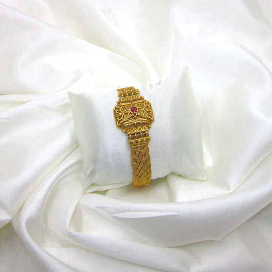 Kusum Heritage Rajwadi Bracelet by ENAVA featuring antique gold finish, floral centerpiece, ruby red stone accent, and intricate braided Rajwadi craftsmanship for weddings and festive wear.