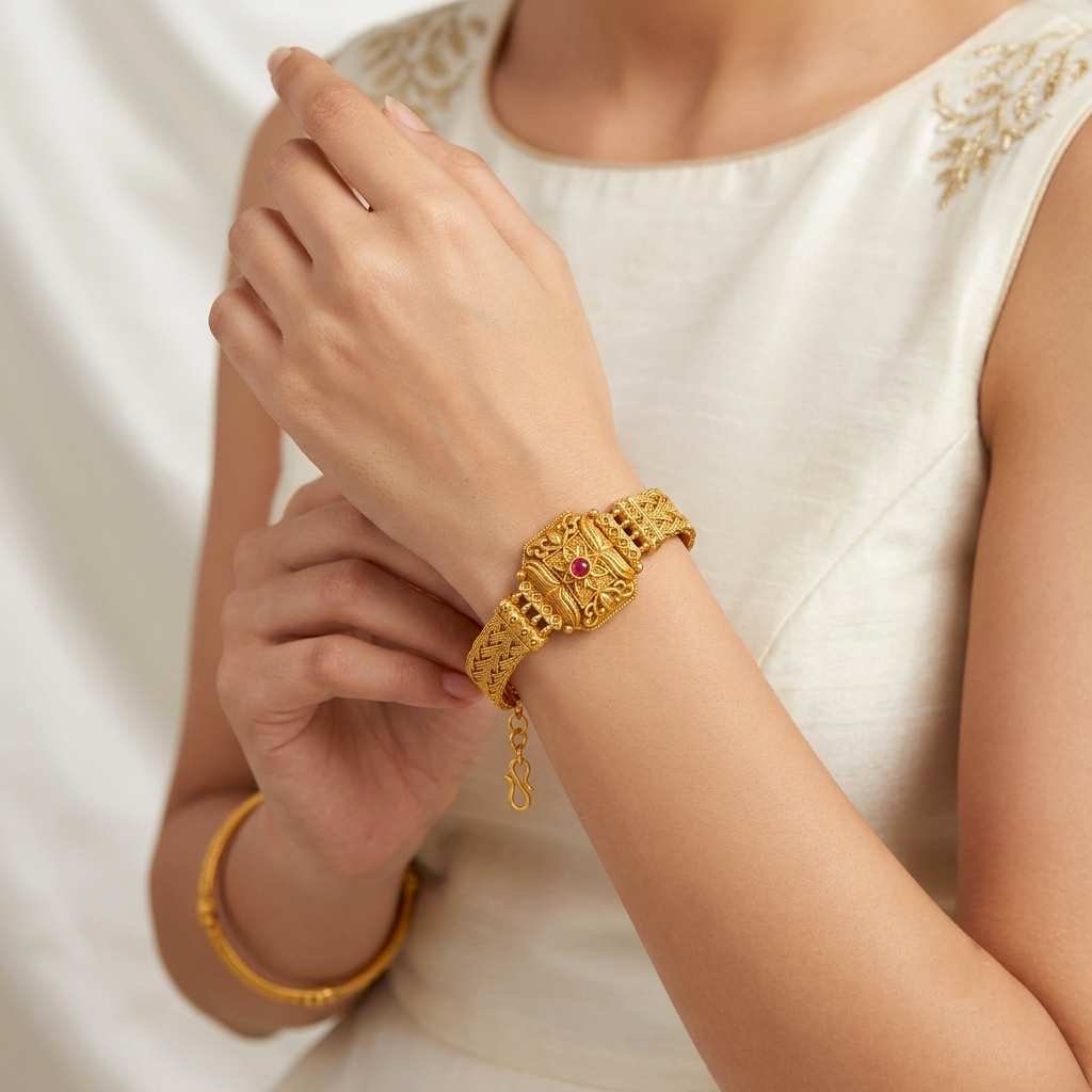 Kusum Heritage Rajwadi Bracelet by ENAVA featuring antique gold finish, floral centerpiece, ruby red stone accent, and intricate braided Rajwadi craftsmanship for weddings and festive wear.