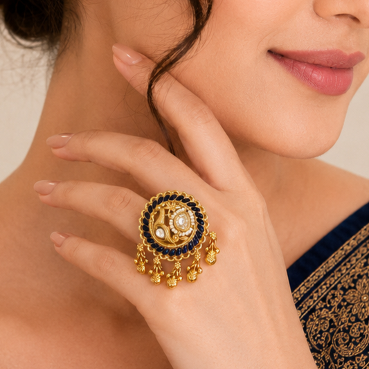 A close-up lifestyle shot of a woman wearing a large, ornate gold ring with dark blue stones and white pearl accents on her hand.