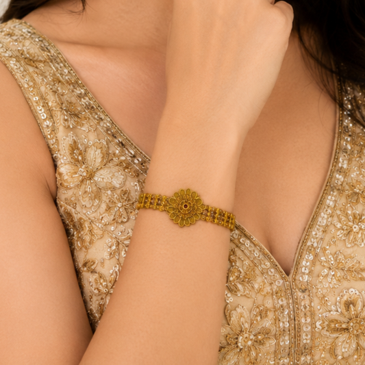 Rajaswi Floral Heritage Bracelet by Enava featuring an antique gold floral design with ruby pink and emerald green stones, intricate heritage detailing, adjustable chain closure, and a premium ethnic statement bracelet for weddings and festive occasions.