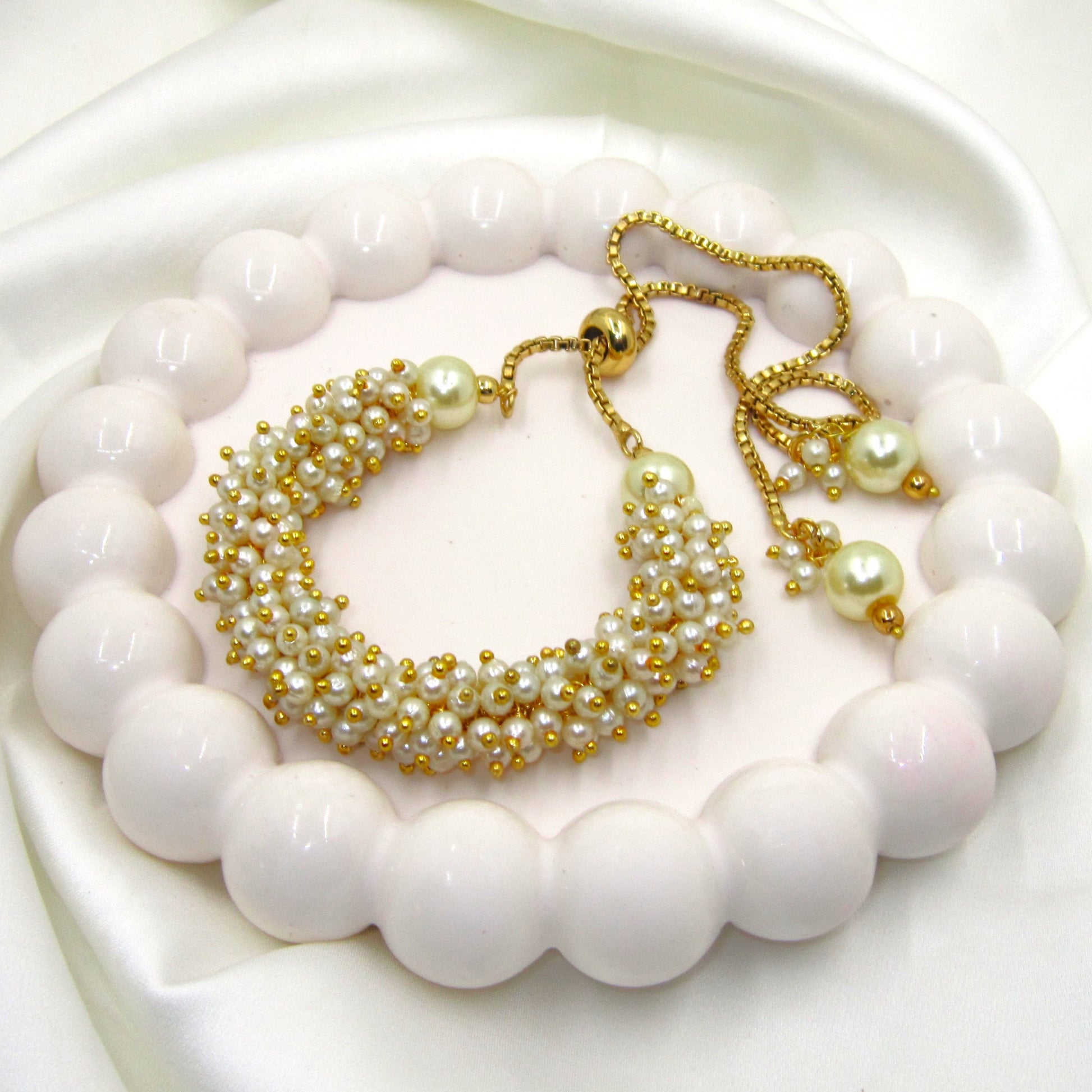 Pearl Heritage Golden Bracelet by Enava featuring handcrafted ivory pearl beadwork, polished gold-tone detailing, adjustable slider chain with pearl drop accents, elegant luxury bracelet for weddings, festive occasions, bridal wear, party styling, and premium ethnic jewellery.