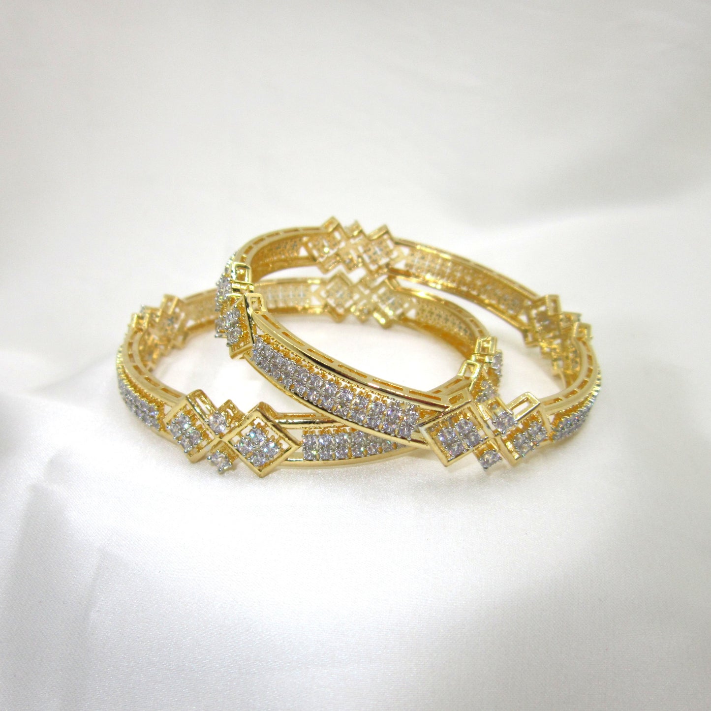 Prestige Gold Plated CZ AD Kada Bangles by ENAVA featuring sparkling clear white Cubic Zirconia American Diamond stones with elegant geometric motifs and premium gold plating. Luxury bridal kada bangles perfect for weddings, receptions, festive occasions, party wear, and designer jewellery collections.