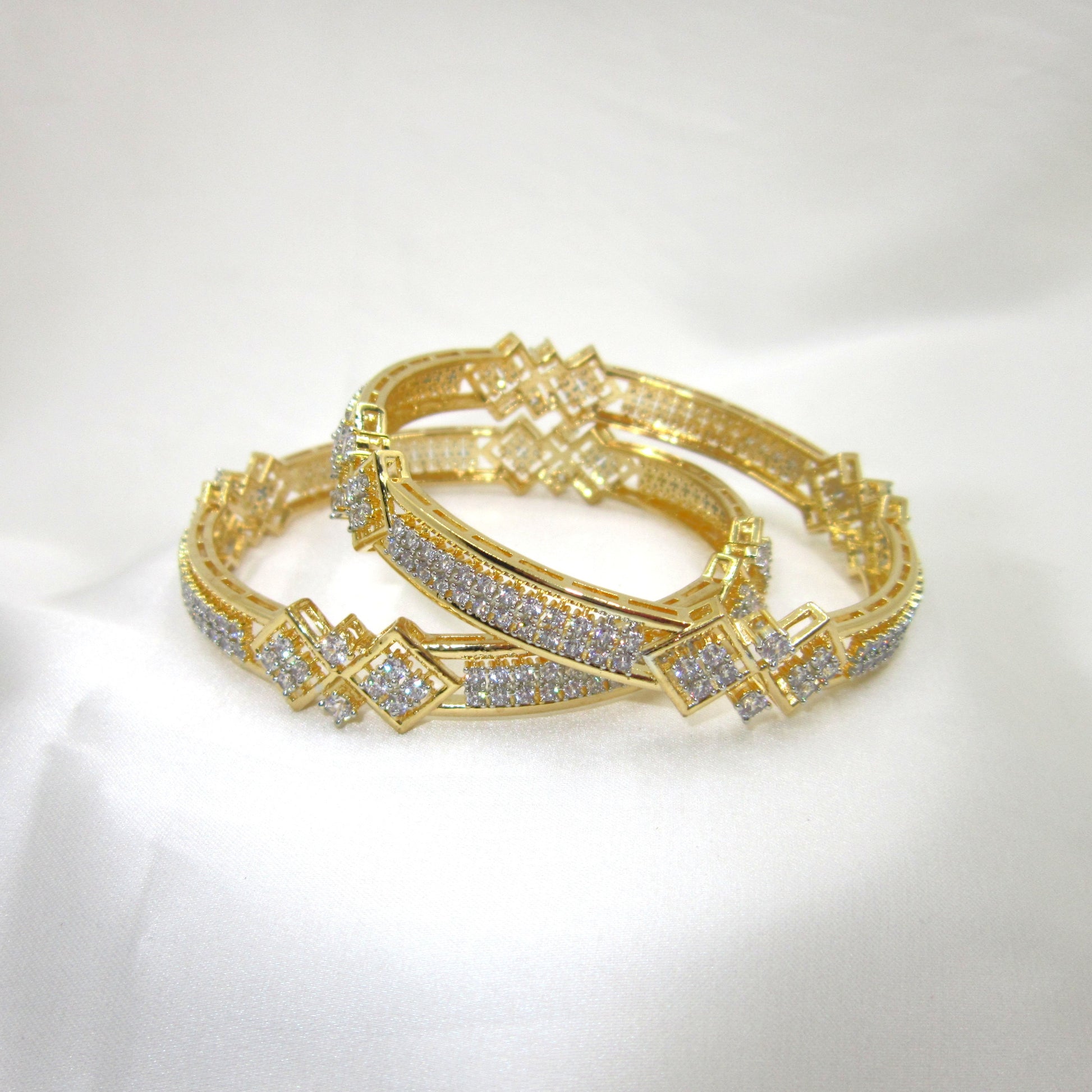 Prestige Gold Plated CZ AD Kada Bangles by ENAVA featuring sparkling clear white Cubic Zirconia American Diamond stones with elegant geometric motifs and premium gold plating. Luxury bridal kada bangles perfect for weddings, receptions, festive occasions, party wear, and designer jewellery collections.