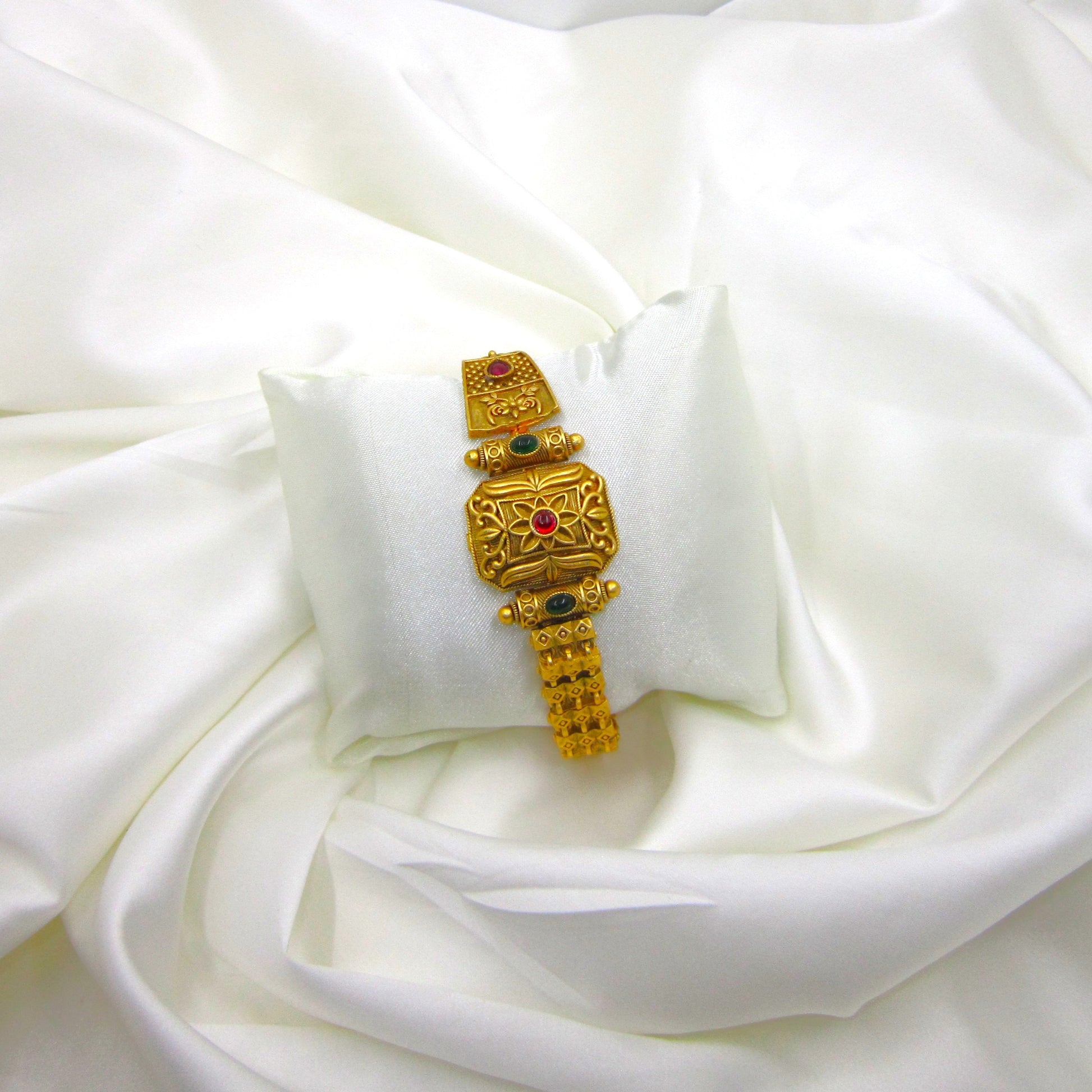 Rajsi Veda Ethnic & Traditional Rajwadi Bracelet by ENAVA featuring an antique gold finish, ruby red centre stone, matching green stone accents, intricate floral engravings, and traditional Rajwadi craftsmanship for weddings and festive wear.