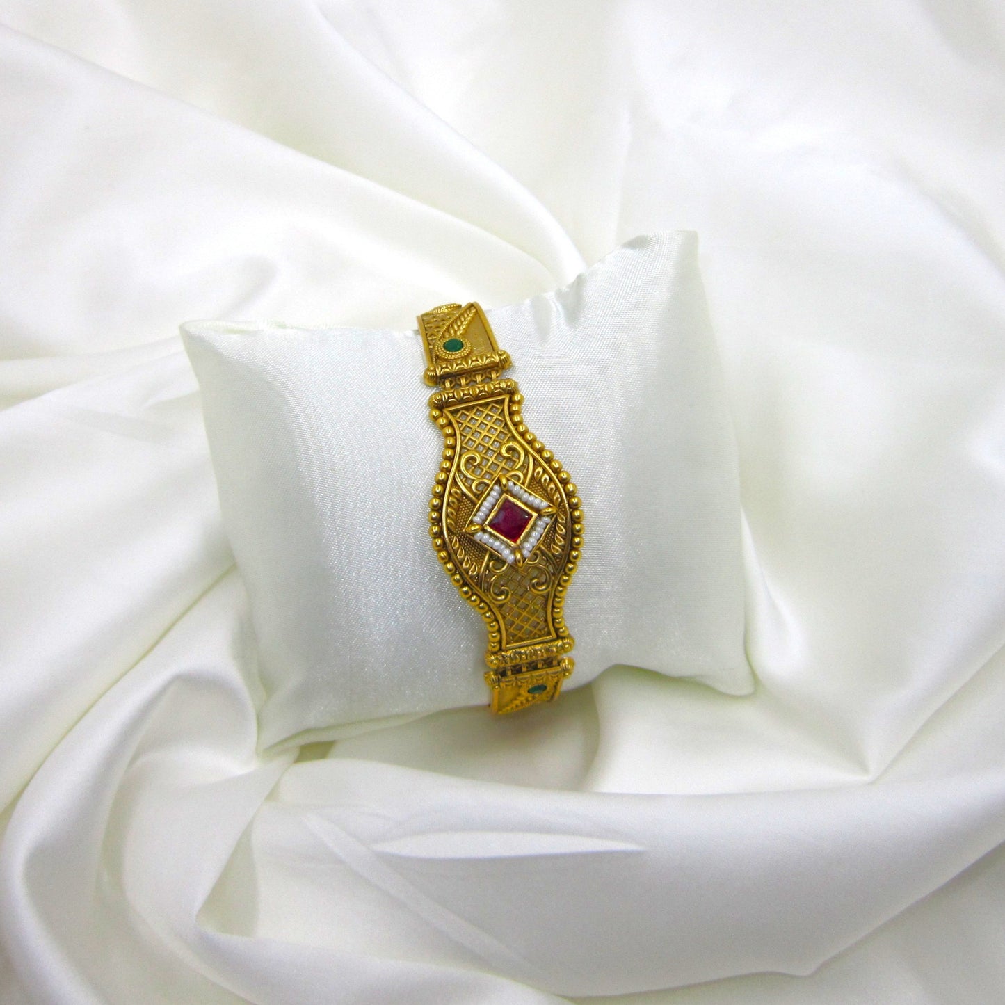 Shagun Spark Rajwadi Bracelet by ENAVA featuring antique gold finish, ruby red centerpiece stone, emerald green accents, and intricate Rajwadi heritage craftsmanship for weddings and festive wear.
