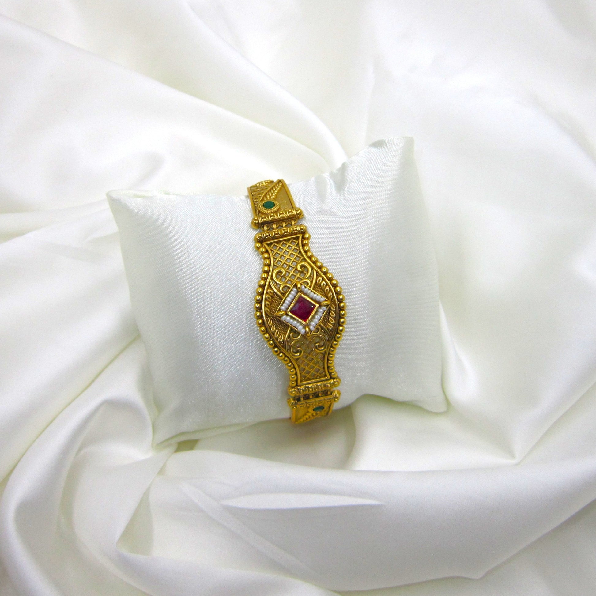 Shagun Spark Rajwadi Bracelet by ENAVA featuring antique gold finish, ruby red centerpiece stone, emerald green accents, and intricate Rajwadi heritage craftsmanship for weddings and festive wear.