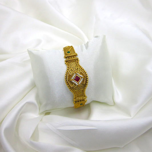 Shagun Spark Rajwadi Bracelet by ENAVA featuring antique gold finish, ruby red centerpiece stone, emerald green accents, and intricate Rajwadi heritage craftsmanship for weddings and festive wear.