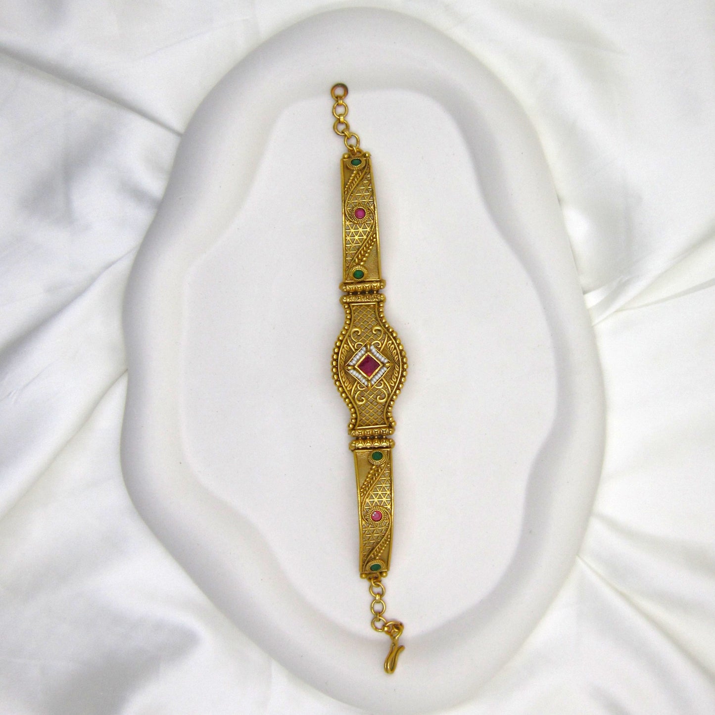 Shagun Spark Rajwadi Bracelet by ENAVA featuring antique gold finish, ruby red centerpiece stone, emerald green accents, and intricate Rajwadi heritage craftsmanship for weddings and festive wear.