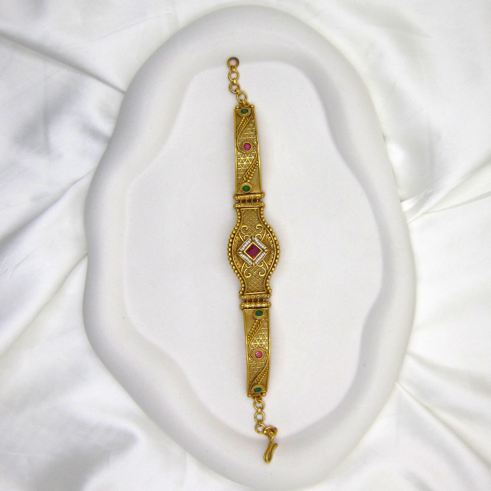 Shagun Spark Rajwadi Bracelet by ENAVA featuring antique gold finish, ruby red centerpiece stone, emerald green accents, and intricate Rajwadi heritage craftsmanship for weddings and festive wear.