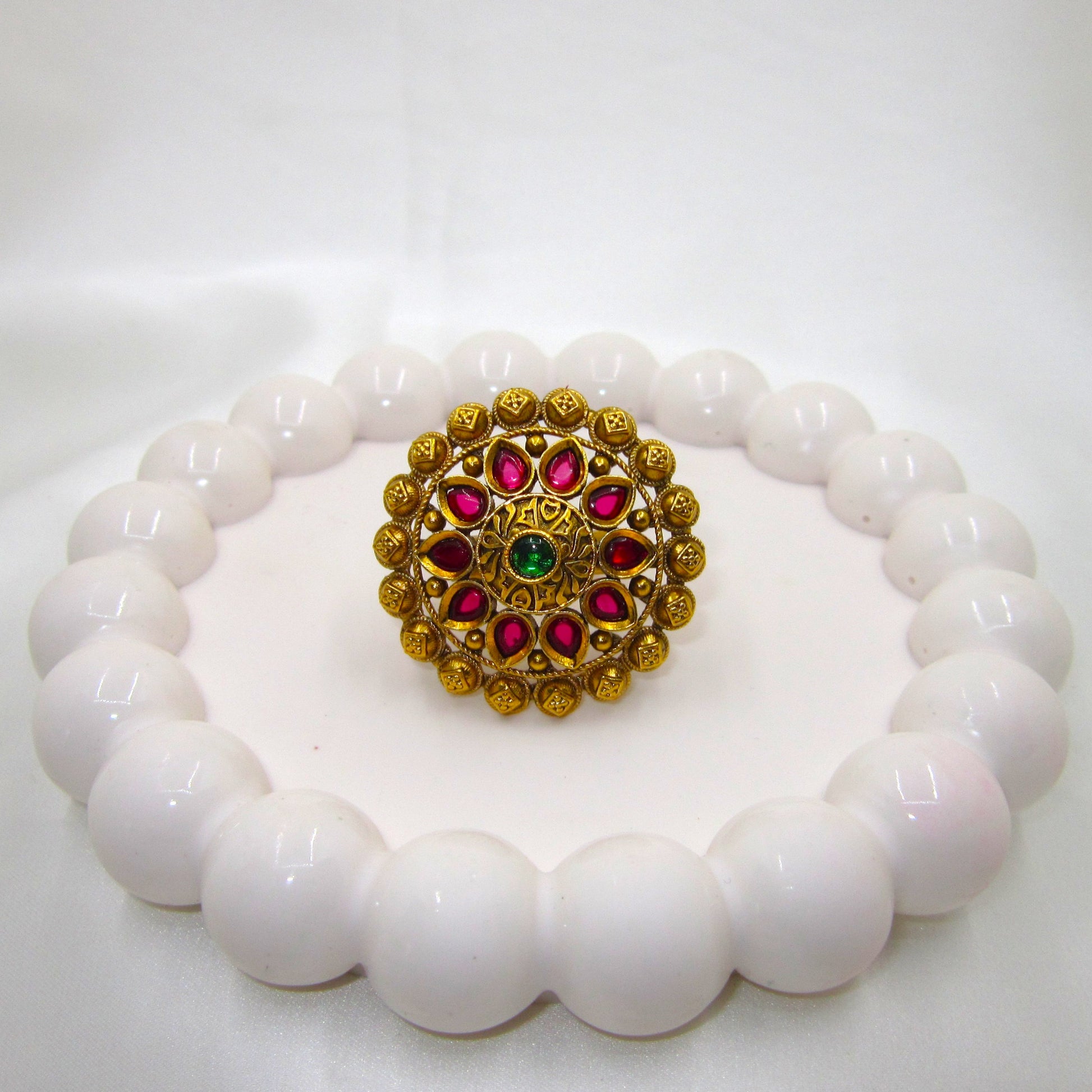 Varnika Temple Ethnic & Traditional Antique Finish Ring by Enava featuring ruby pink teardrop stones, emerald green centre stone, antique gold finish, adjustable temple-inspired statement ring for weddings, festivals, poojas, and ethnic occasions.