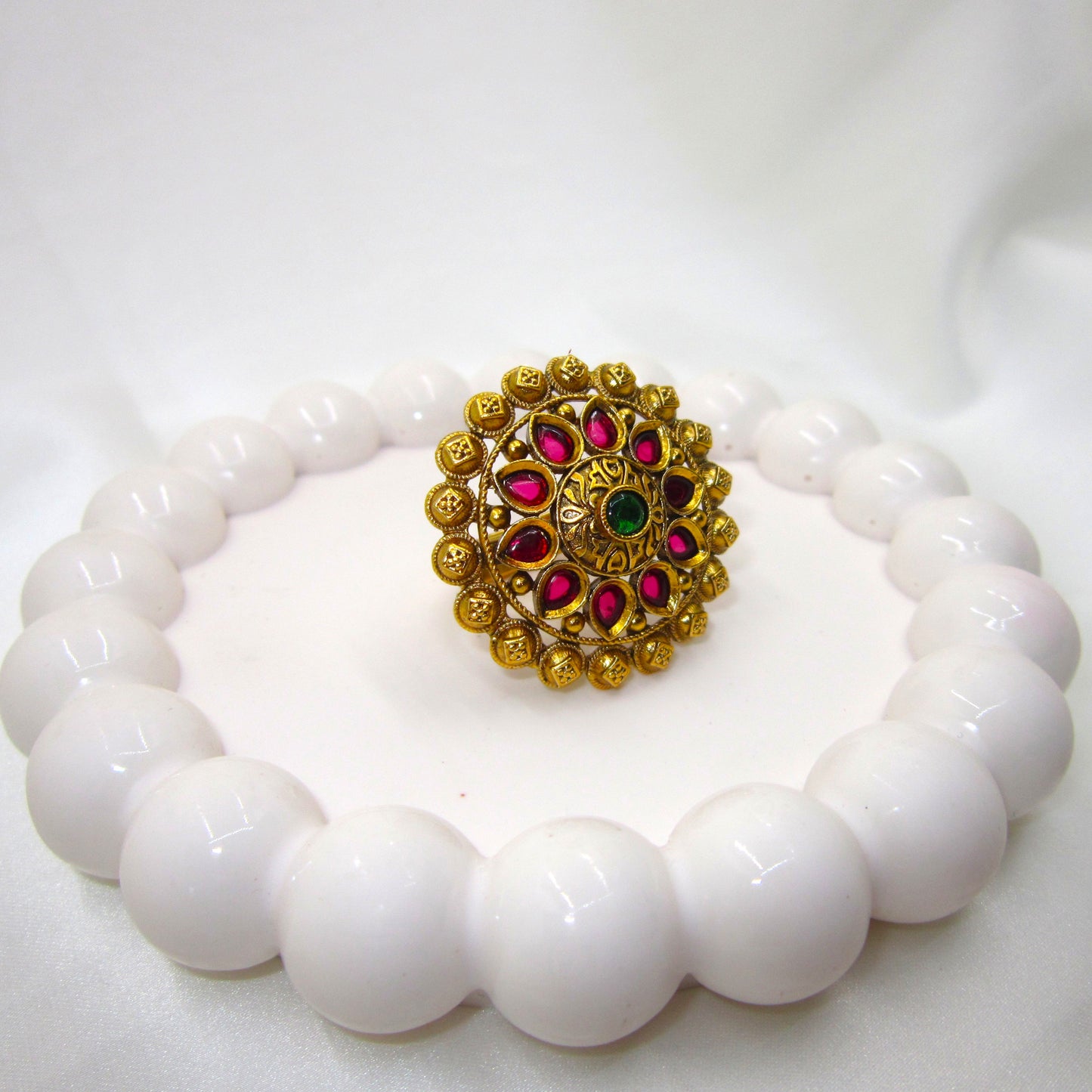 Varnika Temple Ethnic & Traditional Antique Finish Ring by Enava featuring ruby pink teardrop stones, emerald green centre stone, antique gold finish, adjustable temple-inspired statement ring for weddings, festivals, poojas, and ethnic occasions.