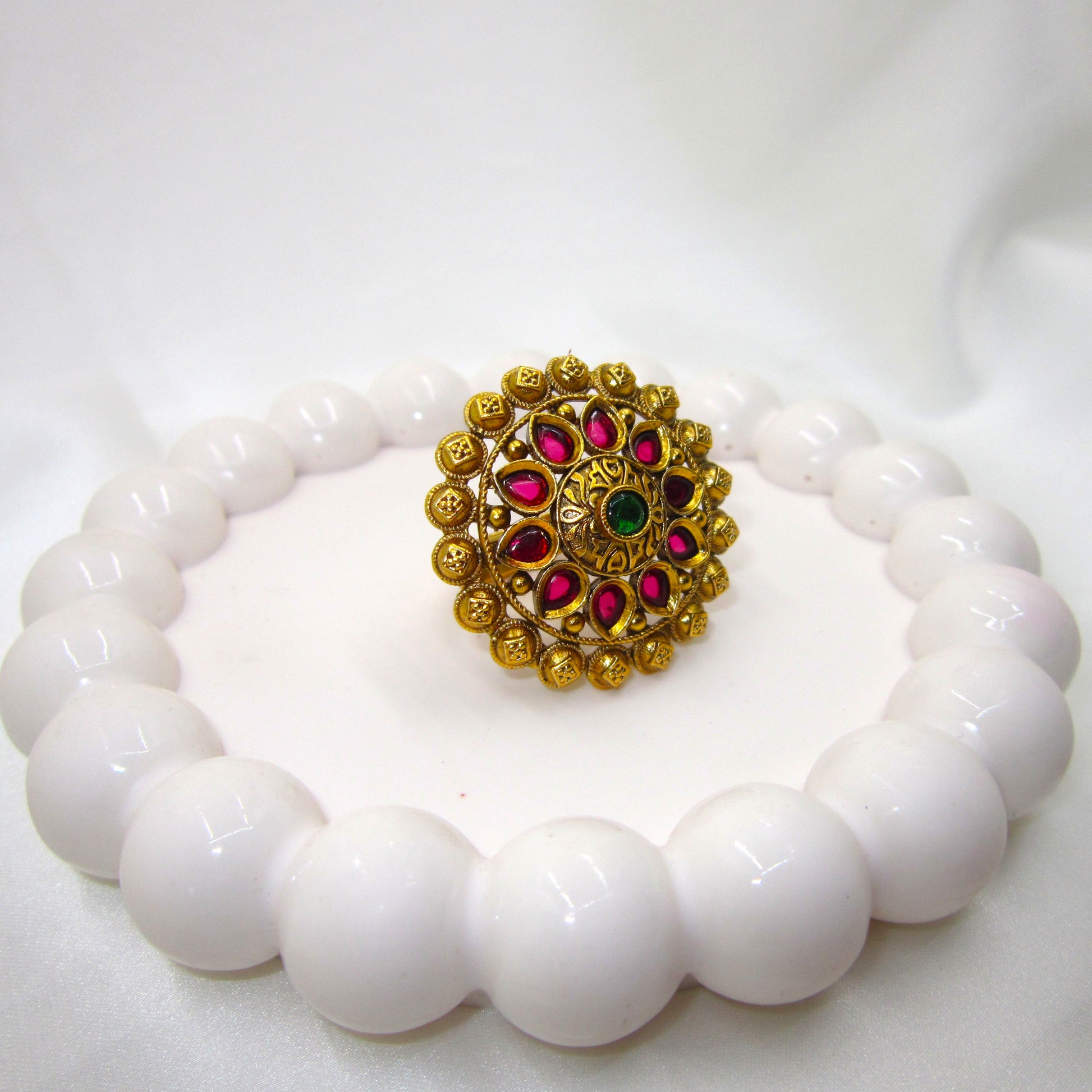 Varnika Temple Ethnic & Traditional Antique Finish Ring by Enava featuring ruby pink teardrop stones, emerald green centre stone, antique gold finish, adjustable temple-inspired statement ring for weddings, festivals, poojas, and ethnic occasions.